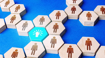 Turning insights into action, a goal of the nonprofit leadership workshop, shown via a network of hexagonal wooden tiles with human silhouettes connected to a central bright blue tile featuring a white lightbulb icon.