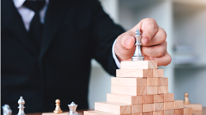A hand placing a chess king on a block pyramid to illustrate the strategic focus taught in this nonprofit leadership workshop.