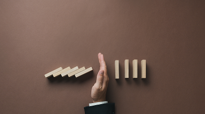 Preventing burnout is a key objective of our nonprofit leadership workshop, visualized by a hand stopping falling dominoes.