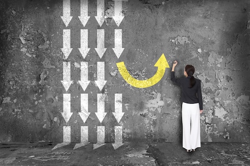 Change direction A woman draws a yellow arrow facing the opposite direction of many white arrows.